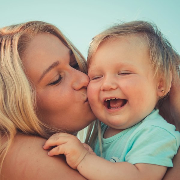 Mãe beijando bebê sorridente